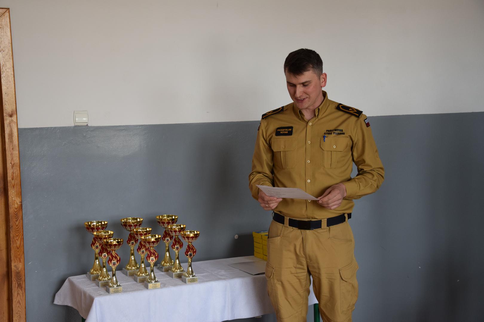 Zdjęcie przedstawia mł. asp. mgr inż.  Przemysława Kotnisa podczas przemówienia 