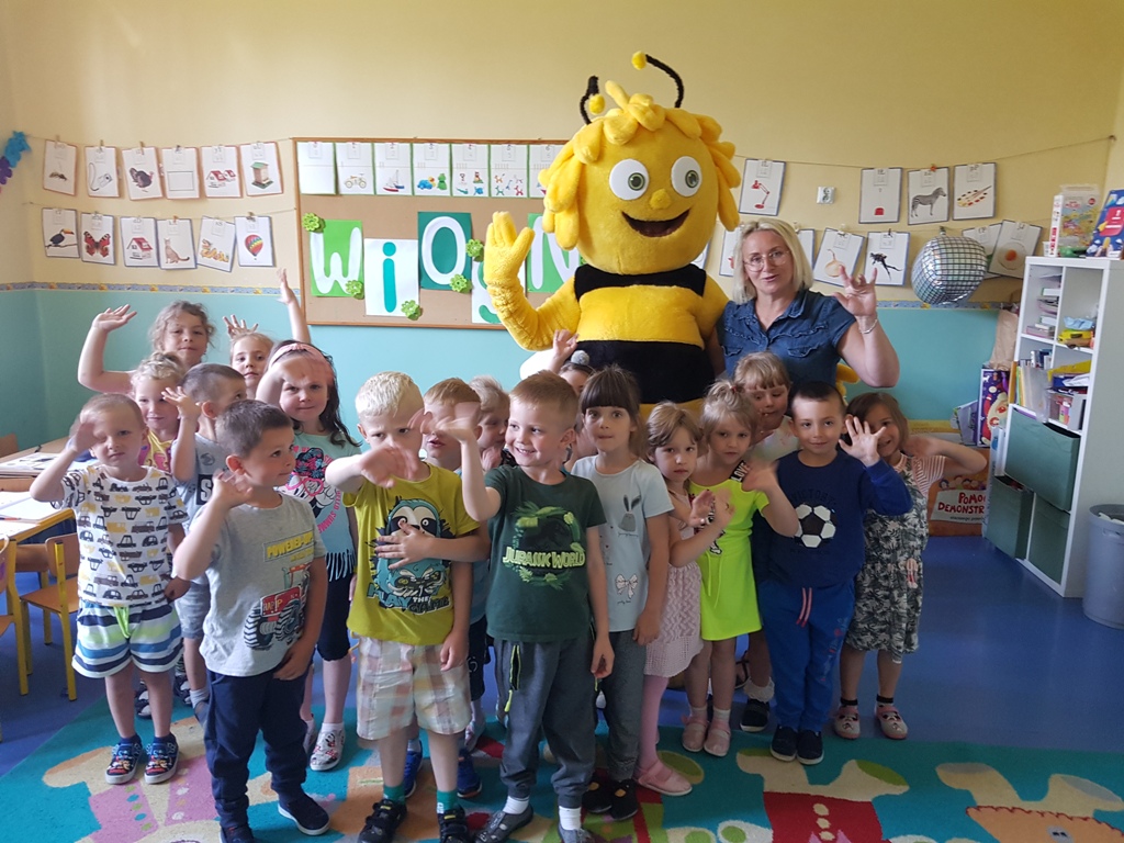 Zdjęcie przedstawia wspólne zdjęcie wspólne zdjęcie dzieci i maskotki pszczoły