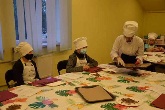 Warsztaty kulinarne - instruktorka rozdaje upieczone ciasteczka