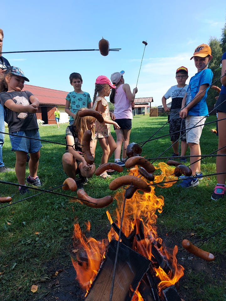 Zdjęcie przedstawiające wspólne pieczenie kiełbasek nad ogniskiem