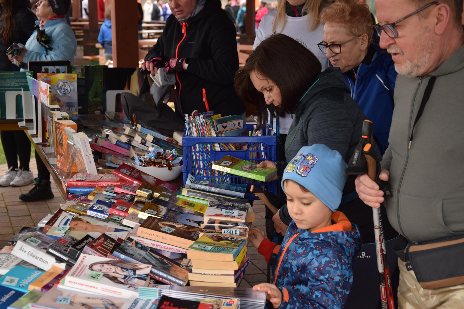 Zdjęcie przedstawia uczestników imprezy przeglądających książki na stoisku prowadzonym przez Bibliotekę Publiczną w Mierzęcicach