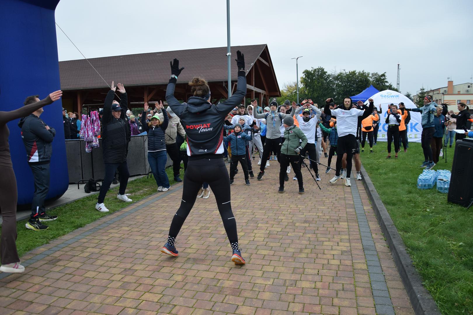 Zdjęcie przedstawia rozgrzewkę uczestnikow biegu