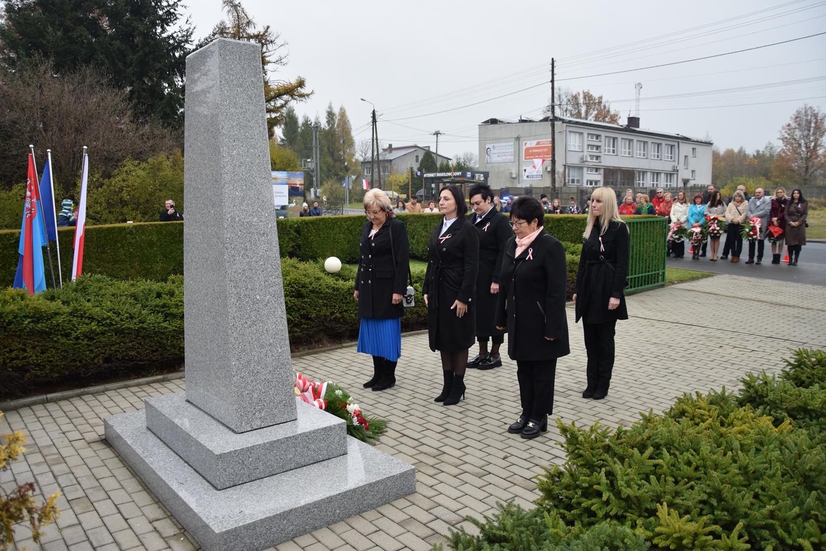 Zdjęcie przedstawia moment składania kwiatów pod pomnikiem