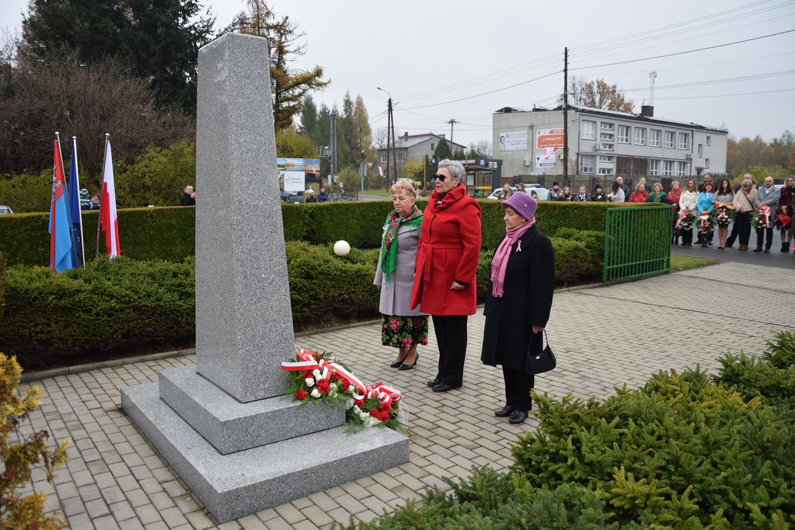 Zdjęcie przedstawia moment składania kwiatów pod pomnikiem