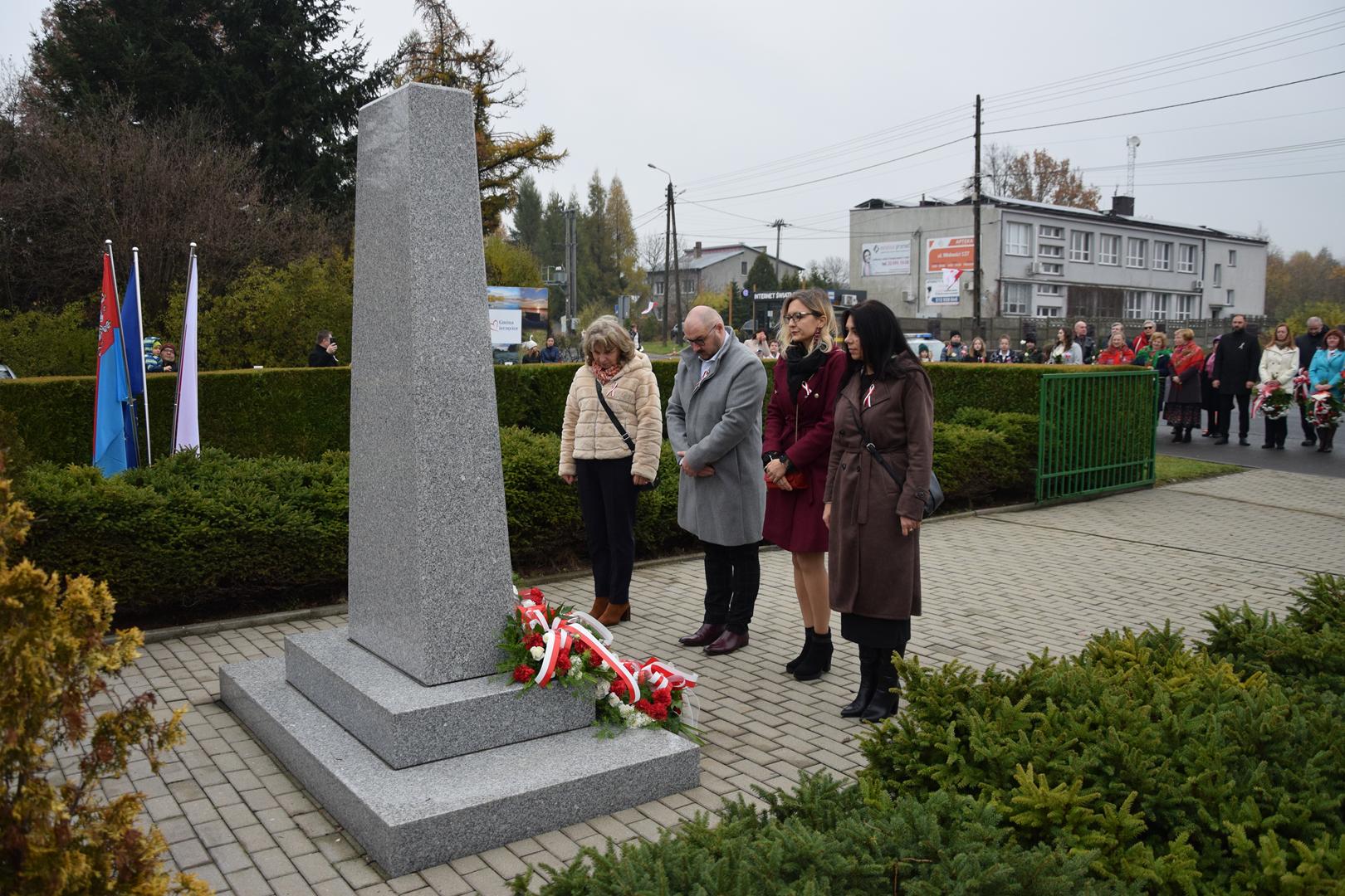 Zdjęcie przedstawia moment składania kwiatów pod pomnikiem