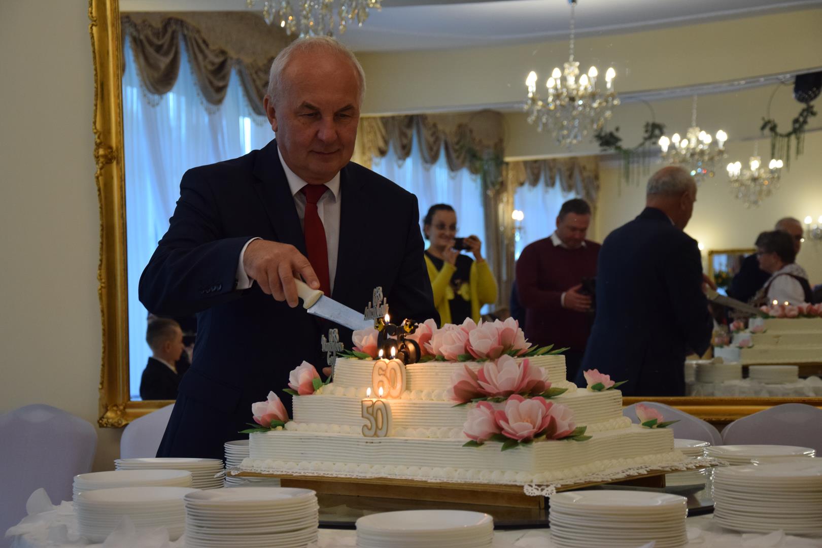 Zdjęcie przedstawia moment krojenia tortu jubileuszowego przez Wójta Gminy Mierzęcice Grzegorza Podlejskiego
